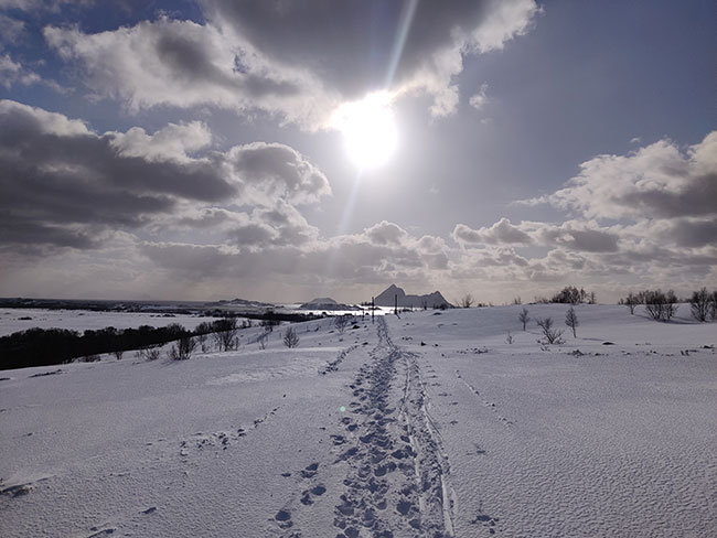 Bilde av fotspor i snøen, sol og fjell