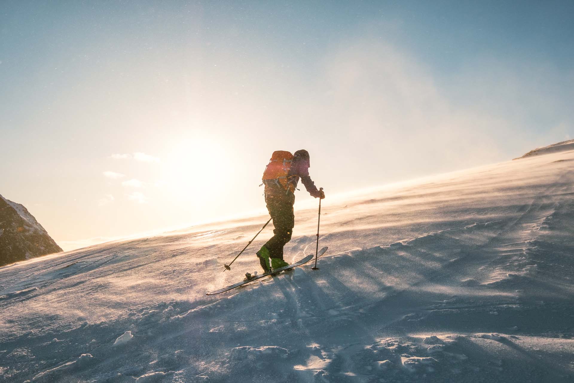 Skigåer på fjelltur i sollys og snystorm.