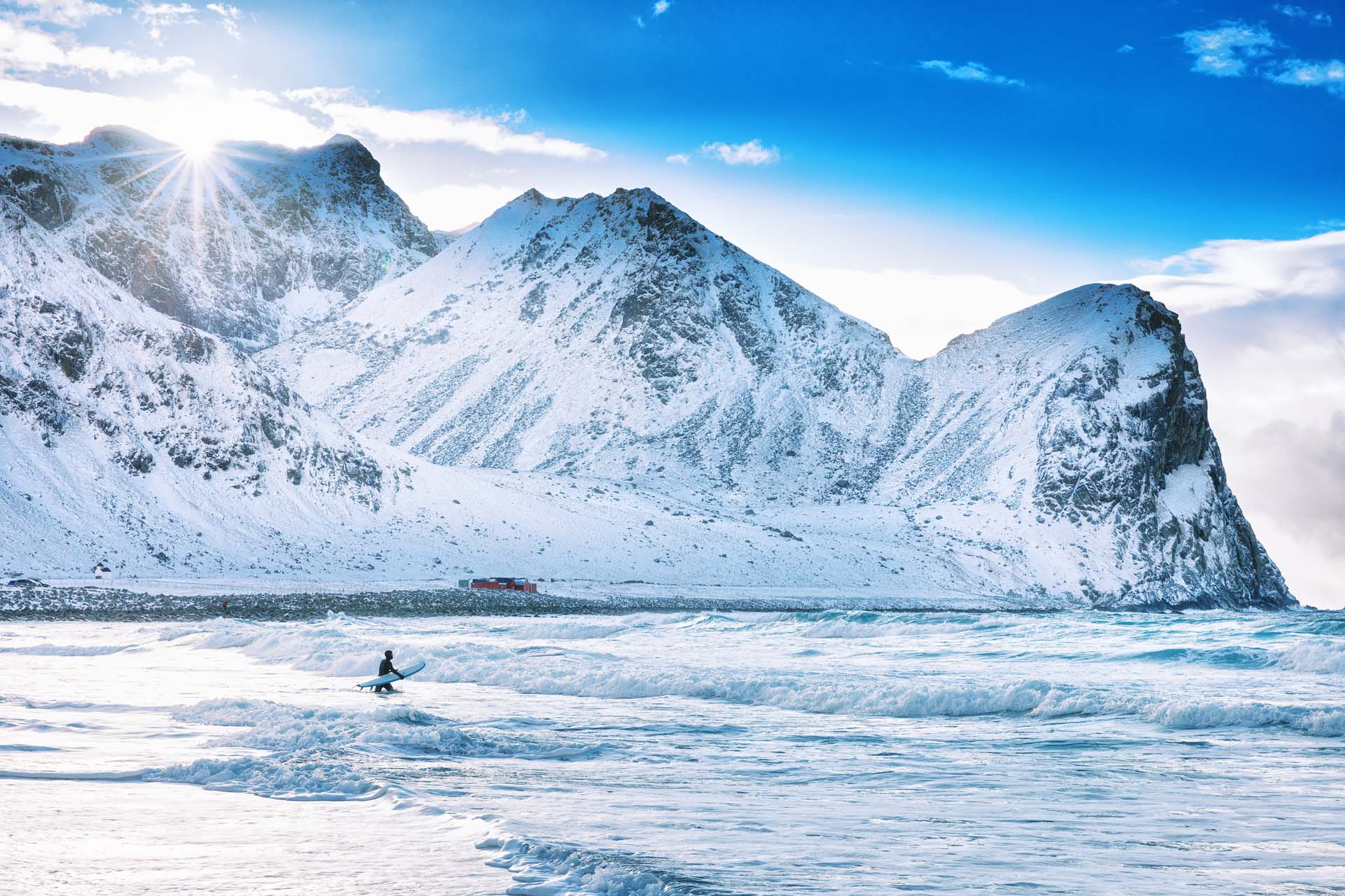 Surfing med snøfylte fjell i bakgrunnen